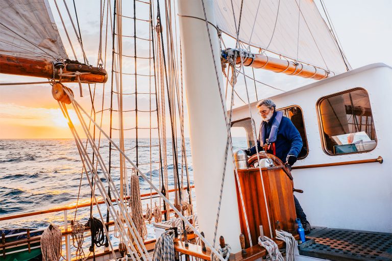 Blue Clipper guest at helm at sunset tall ship  768x512